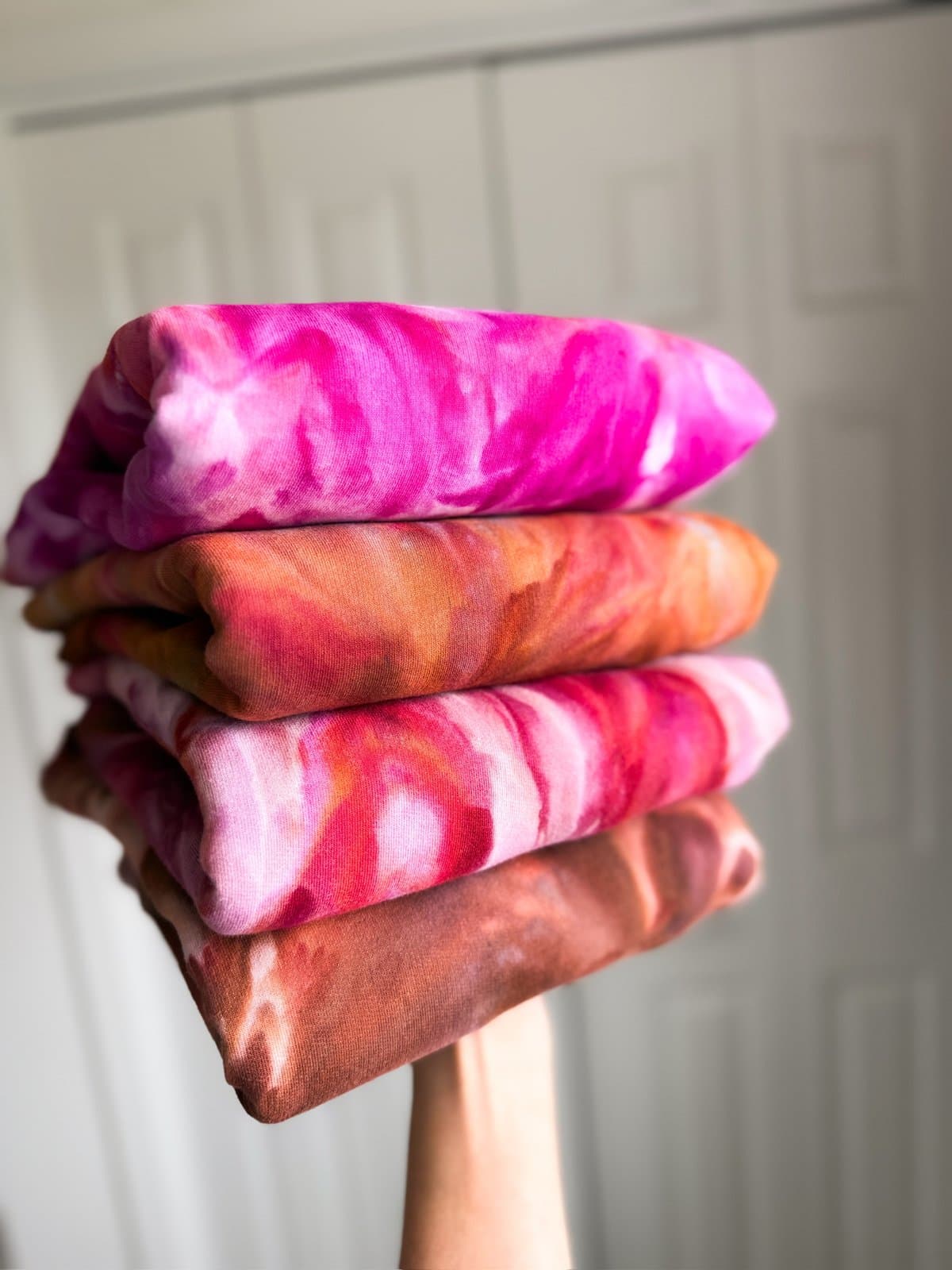 Stack of hand ice-dyed fabric in vibrant pinks and oranges