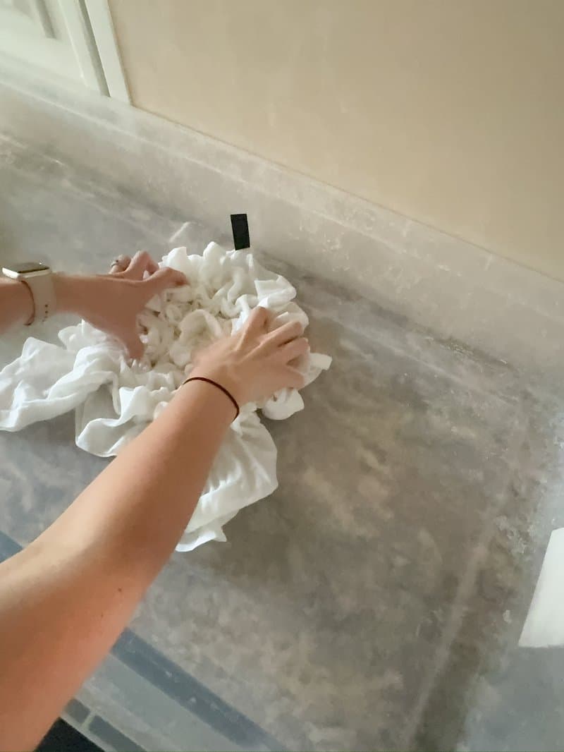 Hands scrunching a white tee in preparation for ice dyeing